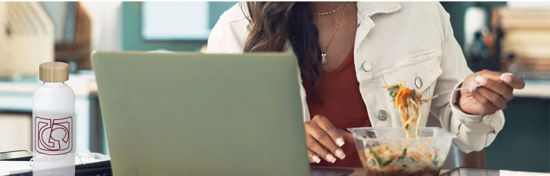 Person sitting at a computer eating food out of a container using custom cutlery