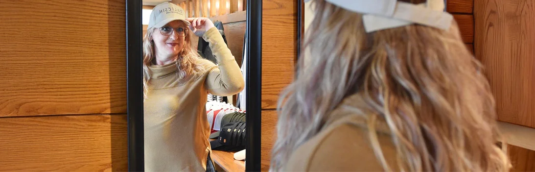 person looking in a mirror while trying on a hat
