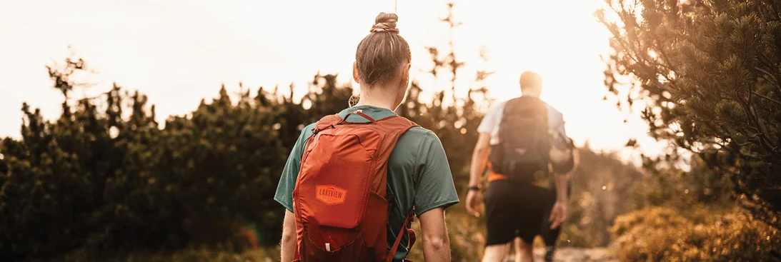 two people hiking on a trail carrying backpacks