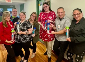 Employees holding custom waterbottle gifts