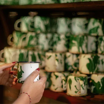 person holding a mug in front of a stack of printed mugs