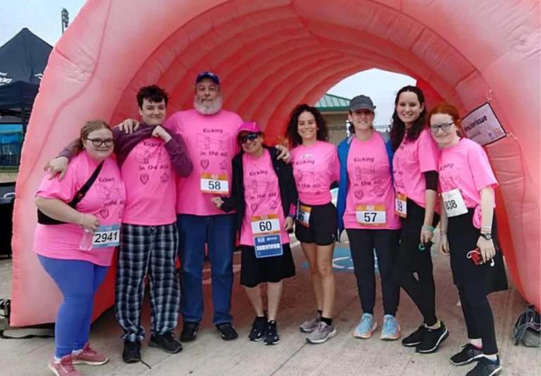 5K runners standing in front of a blow up arch wearing matching team t-shirts.