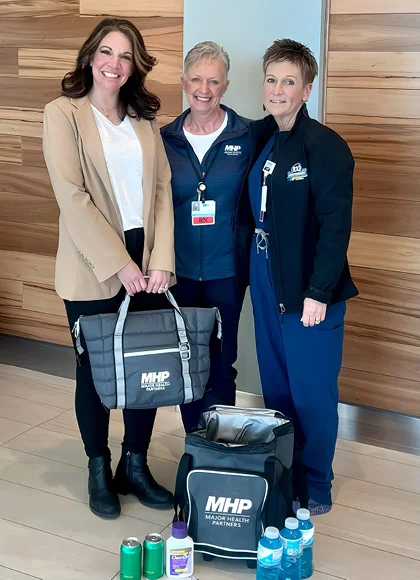 3 Major Health Partners employees holding 2 branded coolers - business care packages