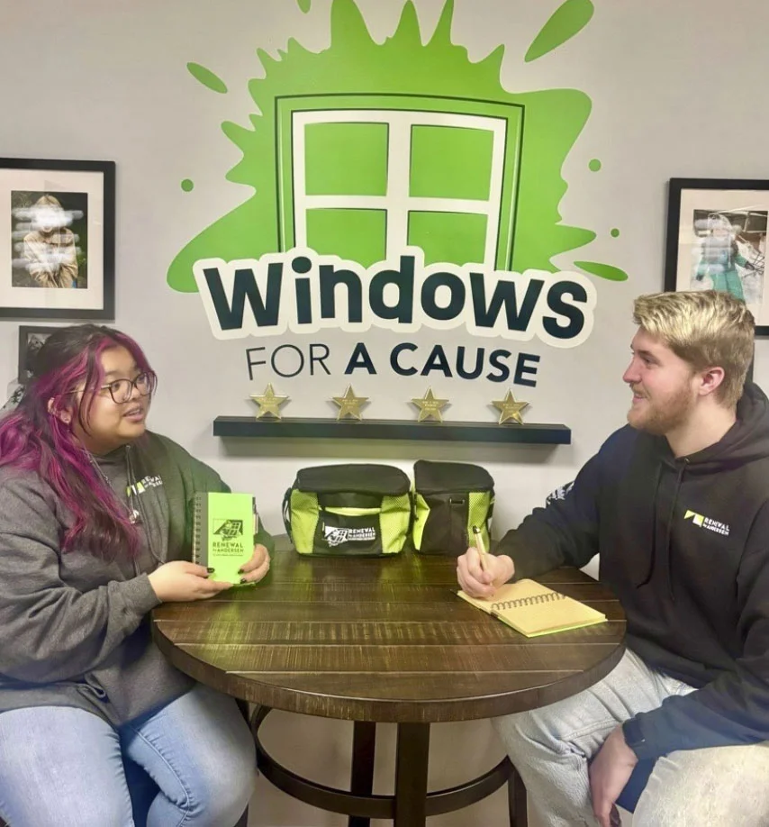 two people sitting at a table surrounded by logoed items