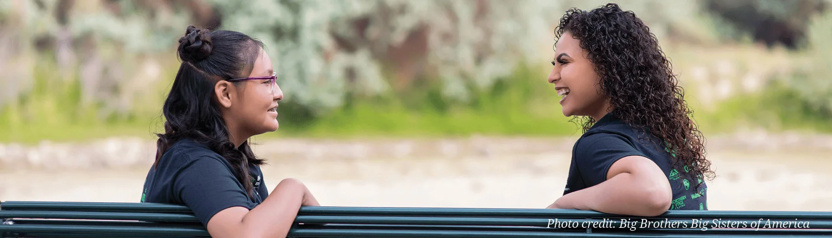 two people sitting on a bench talking