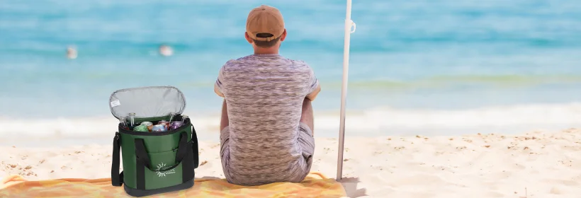 person sitting on a beach next to a cooler