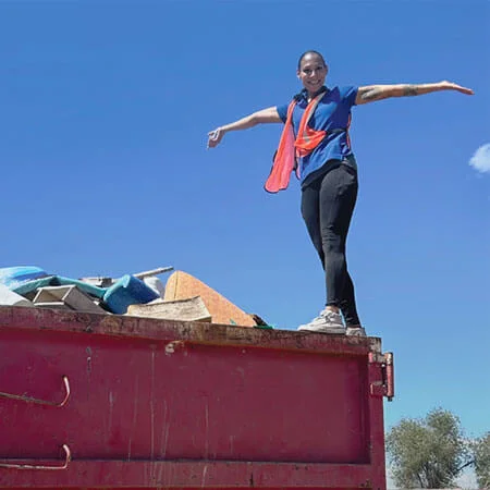 Woman stands on dumpster after community clean up