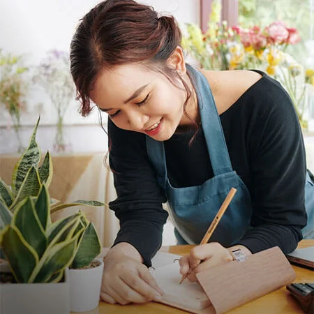 Person working in plan shop writing FSC certified wood pencil and paper