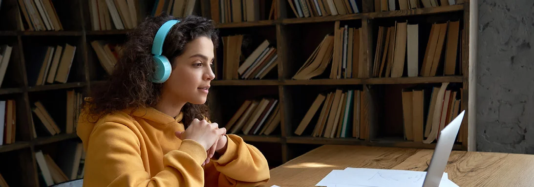 a person sitting at a desk near a computer wearing headphones
