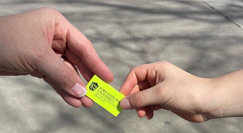 person handing an neon eraser to another person