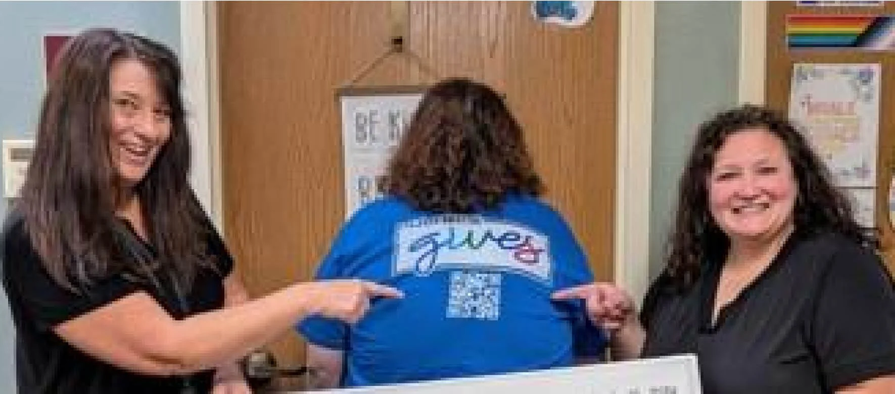 two people pointing to another person wearing a printed t shirt
