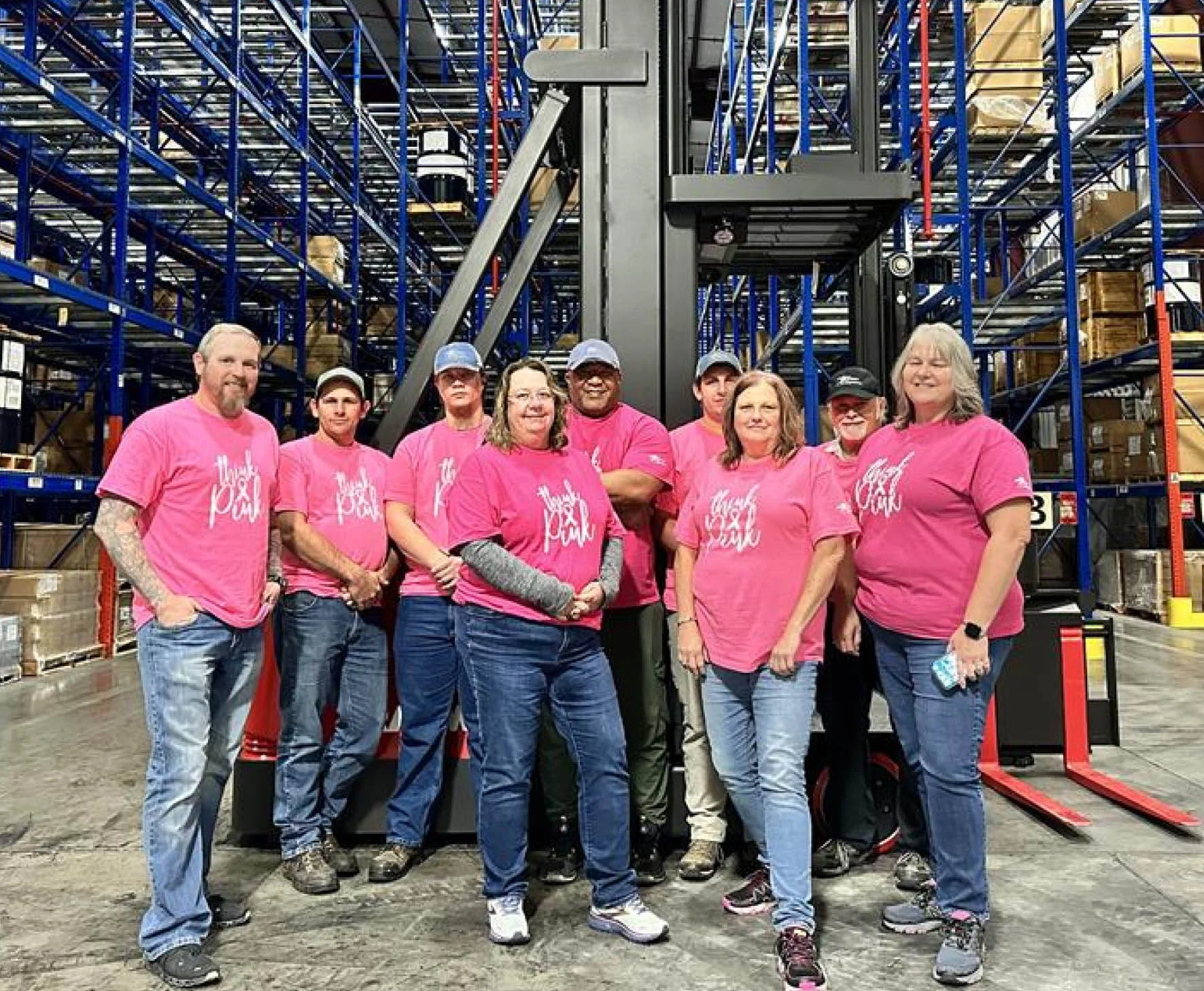 group of people wearing t shirts standing in a factory