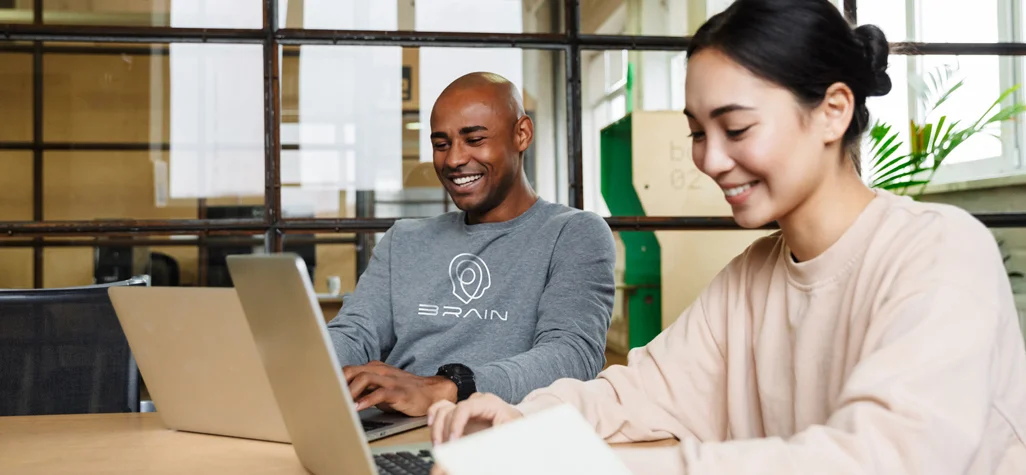 two employees wearing branded company sweatshirts in office