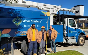 Arbor Masters employees wearing company jackets near a truck