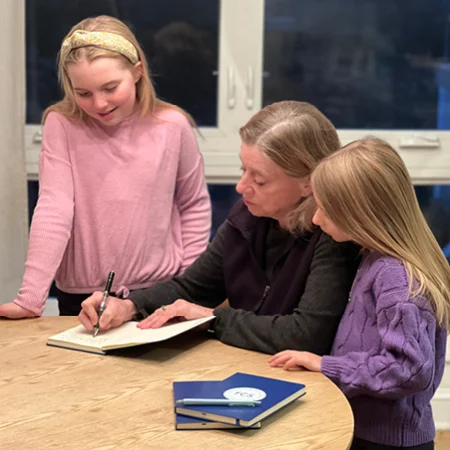 children watching a teacher write in a journal