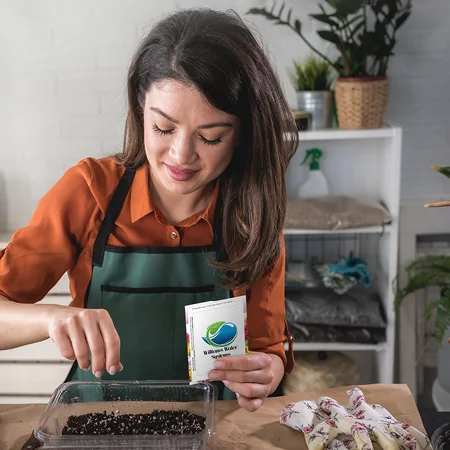 person holding a seed packet sprinkling seeds into soil