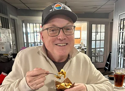 A person wearing a hat and glasses eating food