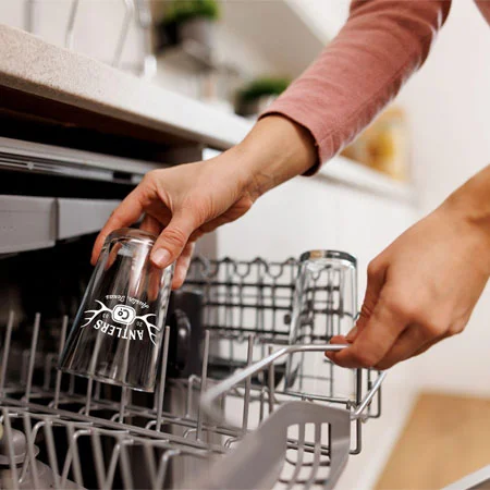 person putting a beer glass into a dishwasher