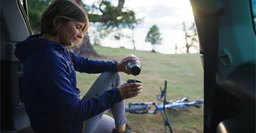 A person pouring coffee from an insulated travel mug