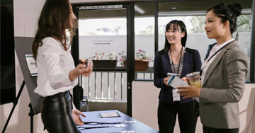 Women Standing by the Registration Booth at a Business Conference