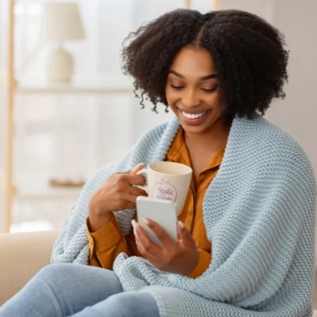 Person wrapped in a blanket and holding mug.