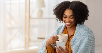 Person wrapped in a blanket and holding mug.