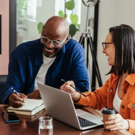 Two laughing coworkers sitting in a conference room.