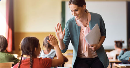 Teacher giving a high-five to a student in a classroom setting.