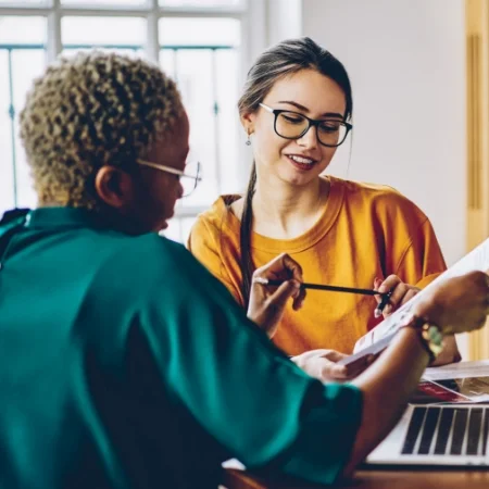 Two people sitting at a table reviewing a document together.