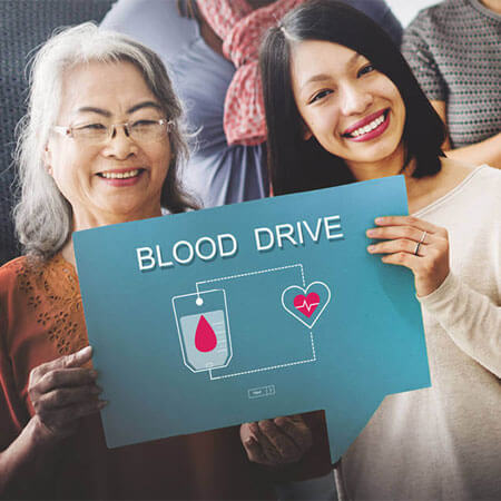 two people holding up a blood drive sign