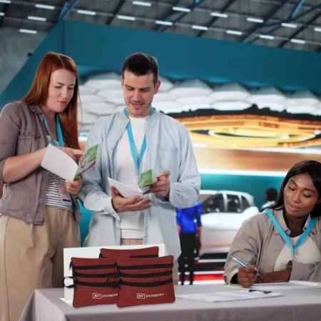 Two people wearing lanyards and working at a trade show booth.