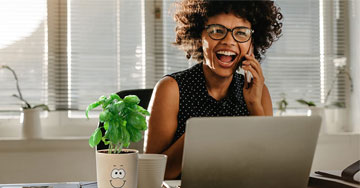 person talking on a phone sitting by a computer