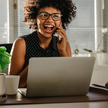 person talking on a phone sitting by a computer