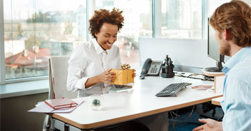 person sitting at a desk holding a gift