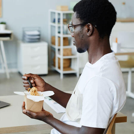 person sitting at a table eating noodles