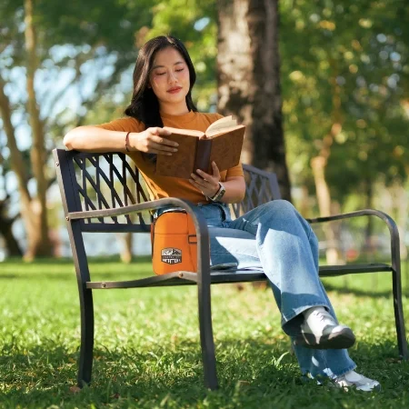 Person sitting on a bench in the park reading a book in the spring.